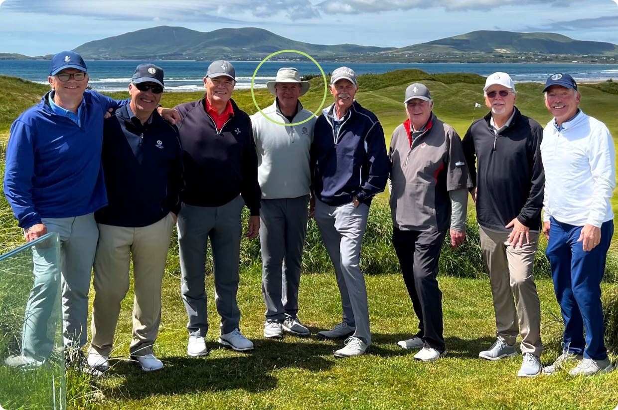 group of men smiling on a golf course near the sea