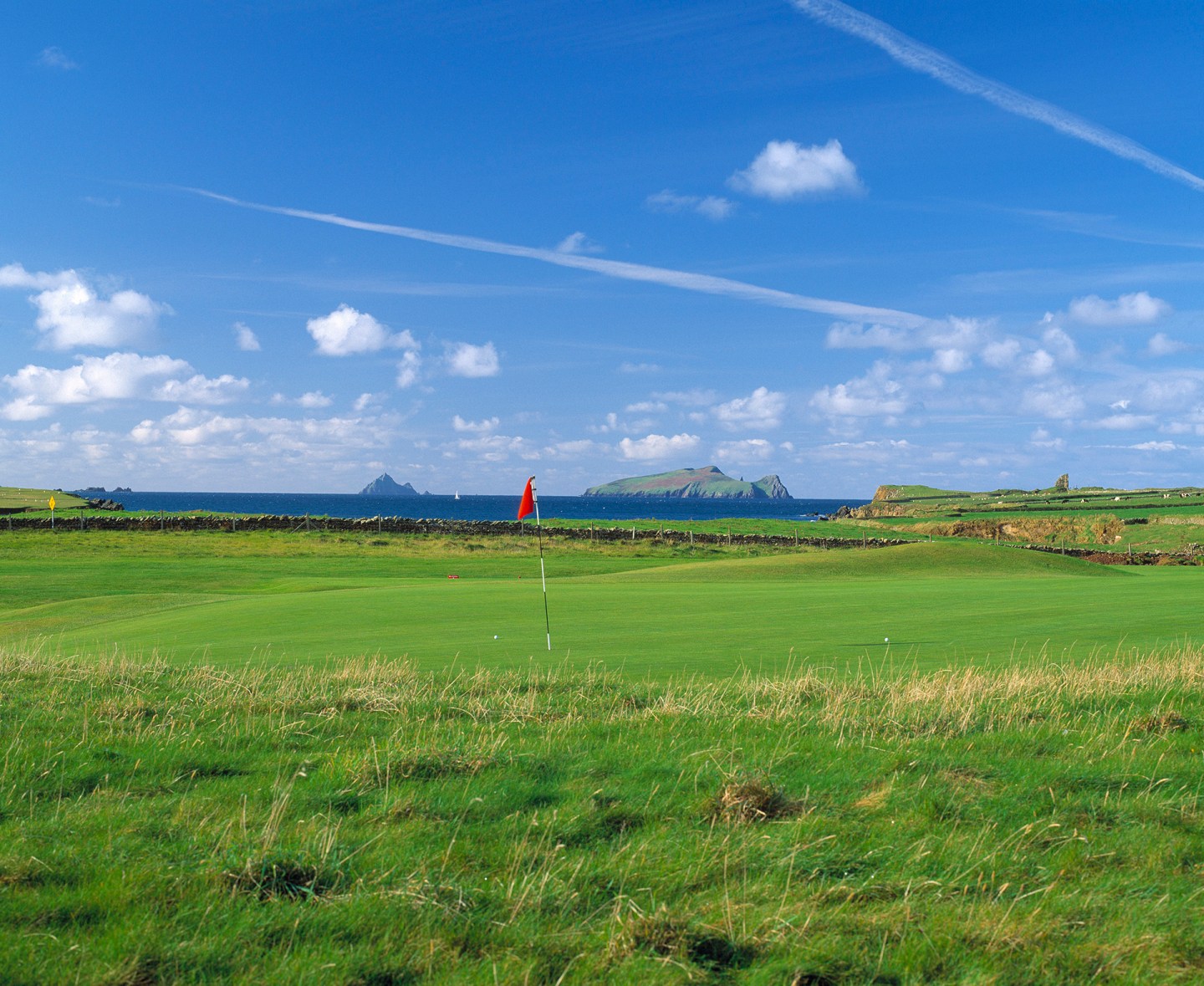 Seaside golf course with red flag near hole