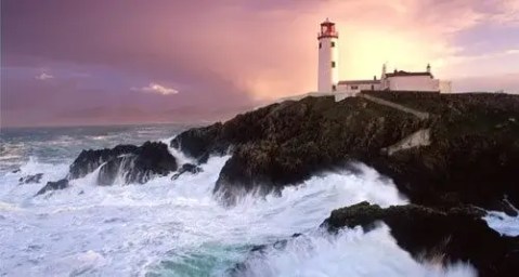 fanad lighthouse with waves crashing against coast