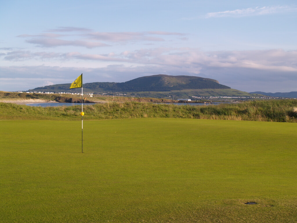 golf course with yellow flag and mountains in background