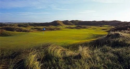 flat golf course surrounded by dunes