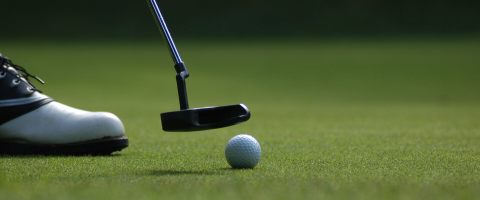 golf putt with ball and golf shoe on grass
